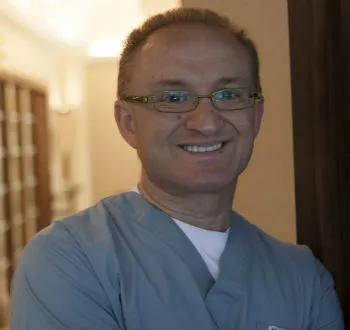 A man in a scrub suit smiling at the camera.