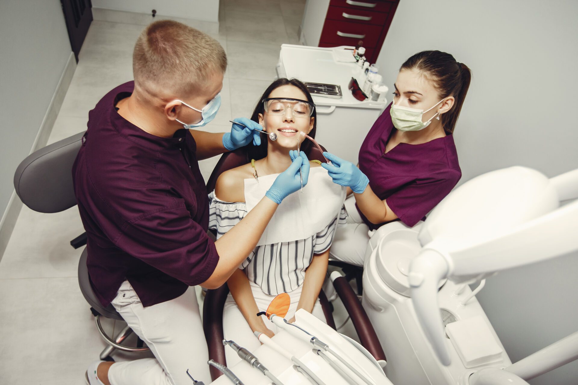 The dentist treats the girl's teeth along with an assistant