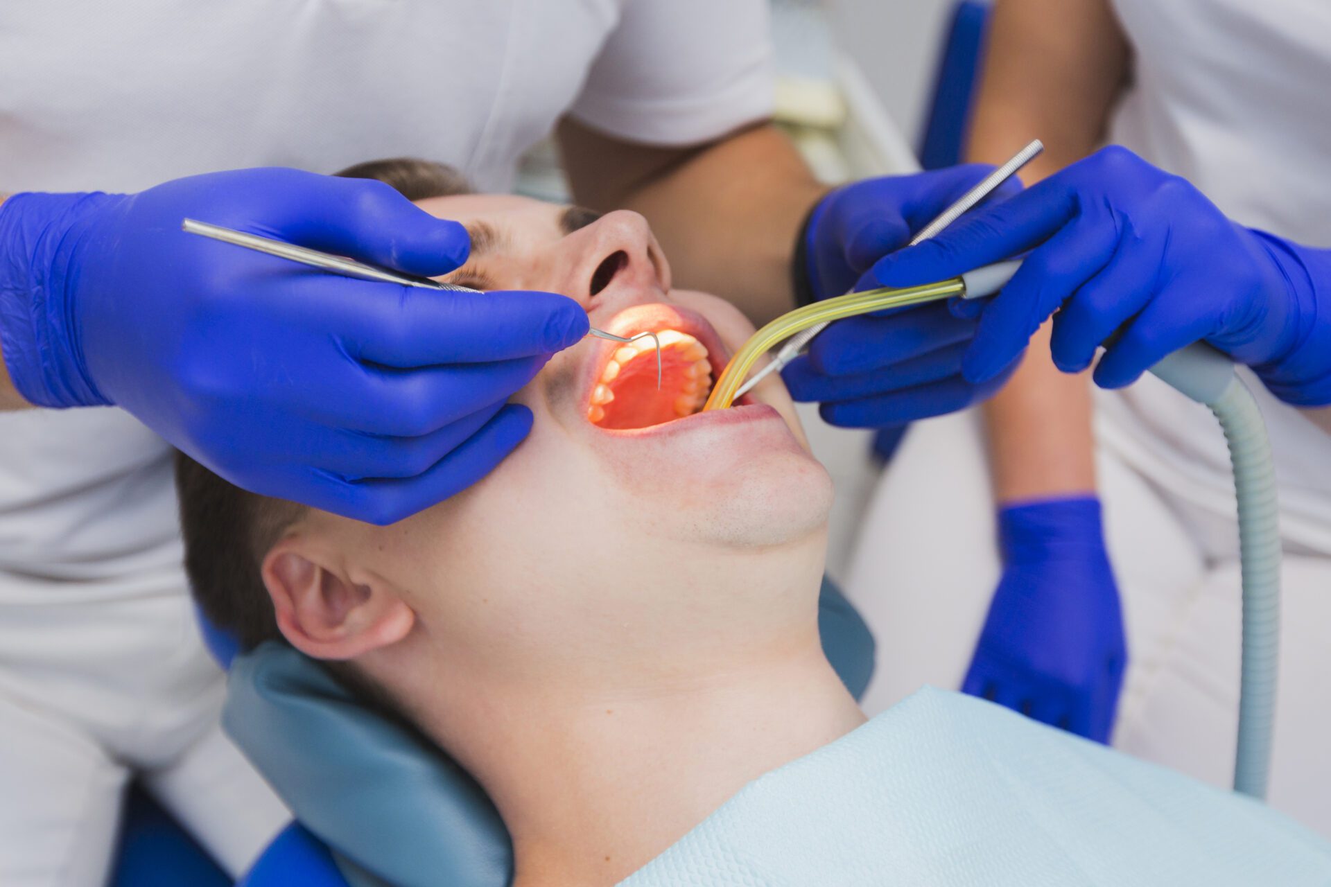 A dentist performs a teeth cleaning on a man in a dental office, highlighting the importance of oral hygiene