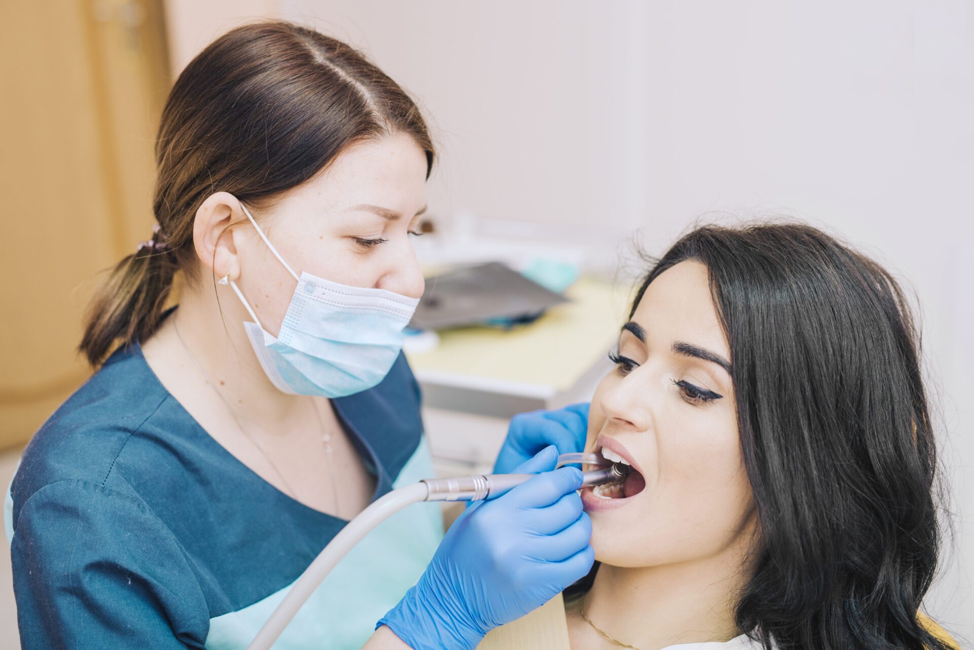 A dentist performs a teeth cleaning on a woman in a clinical setting, highlighting the importance of oral hygiene